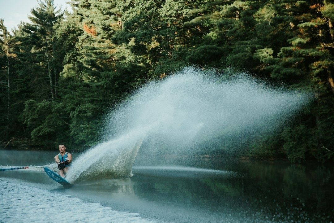 Wasserskifahrer zieht in einer Kurve eine große Spritzwasserfontäne