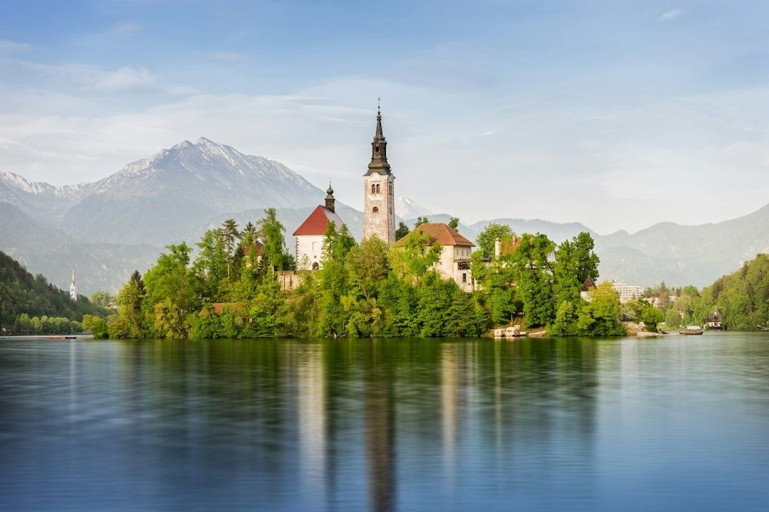 Historische Kirchen- und Schlossanlage auf einer Insel im See vor Alpenkulisse
